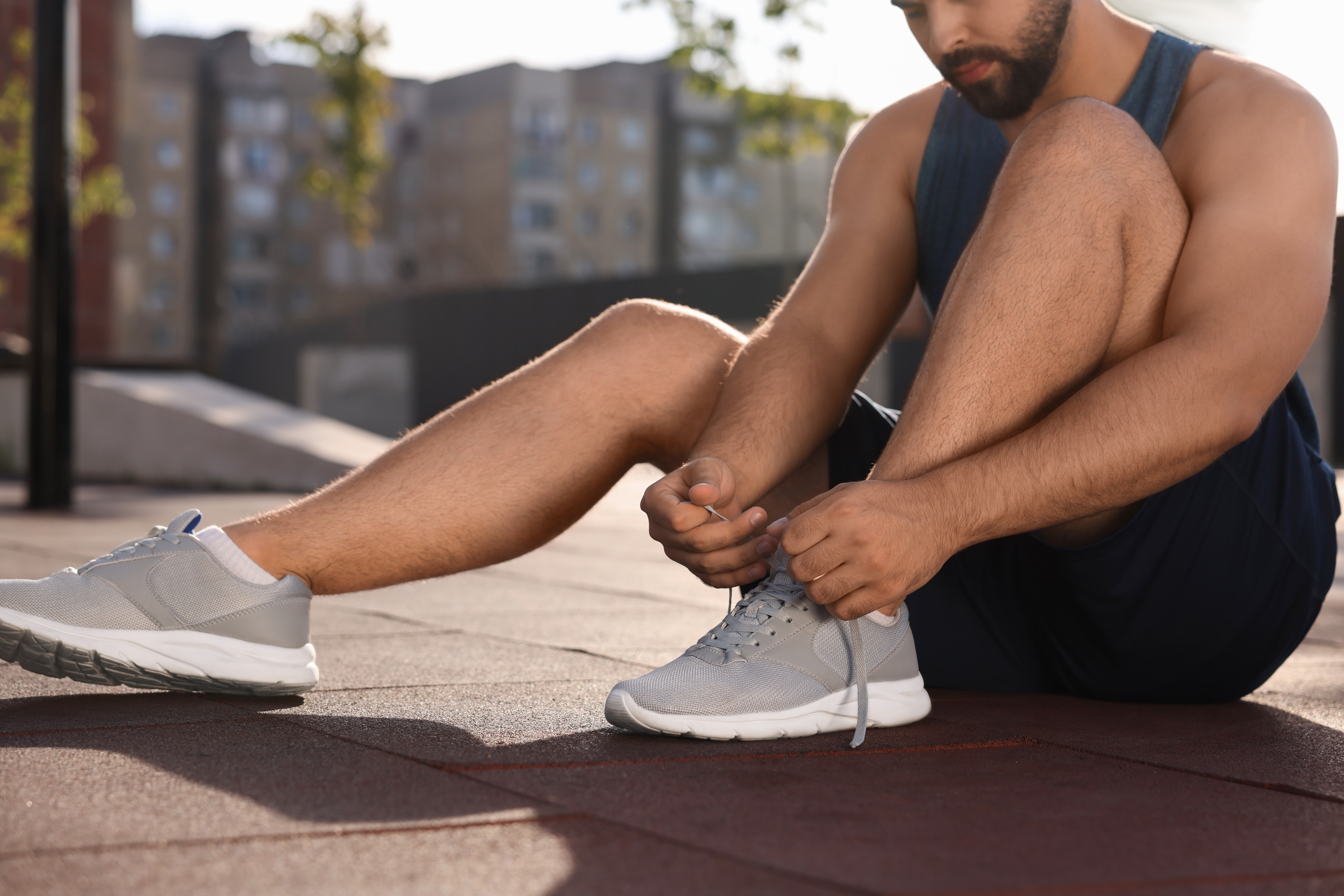 Man tying shoelaces before running outdoors on sunny day, closeup