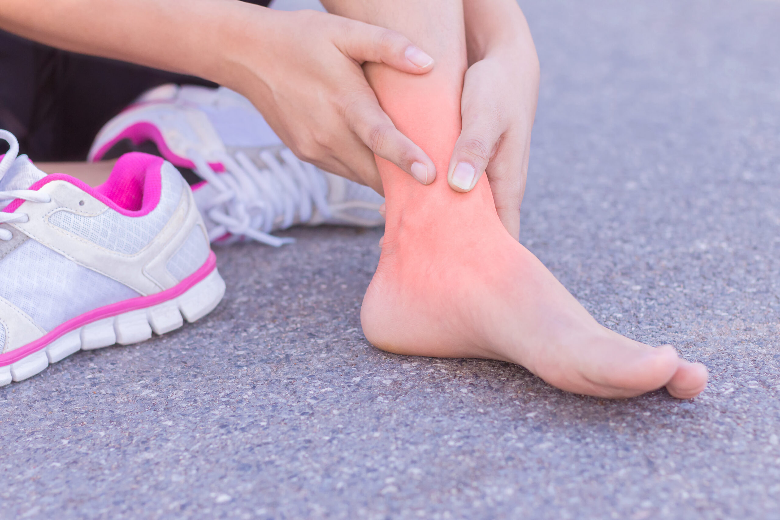 Young woman massaging her painful foot from exercising and runni Young woman massaging her painful foot from exercising and running