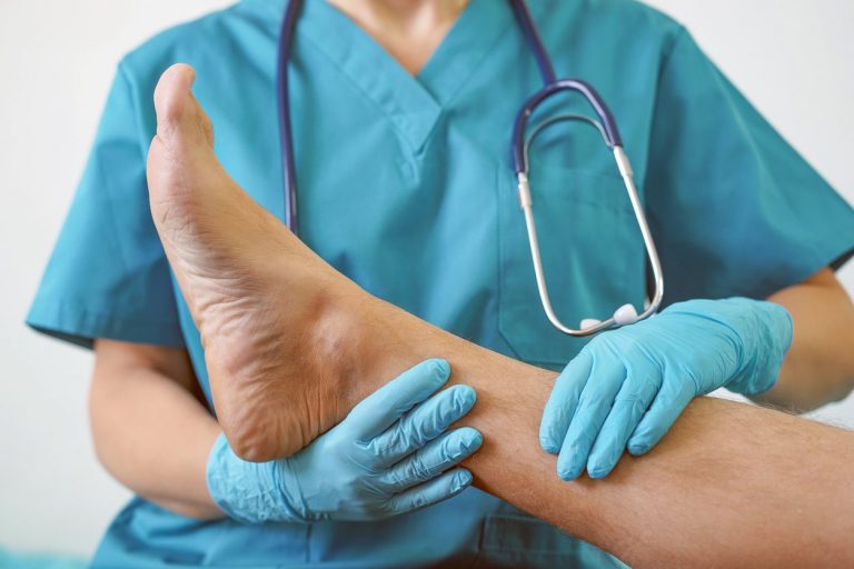 Podiatrist holding a person's leg examining their foot and ankle for diagnosis and treatment
